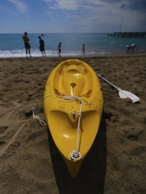 a yellow kayak sitting on top of a sandy beach