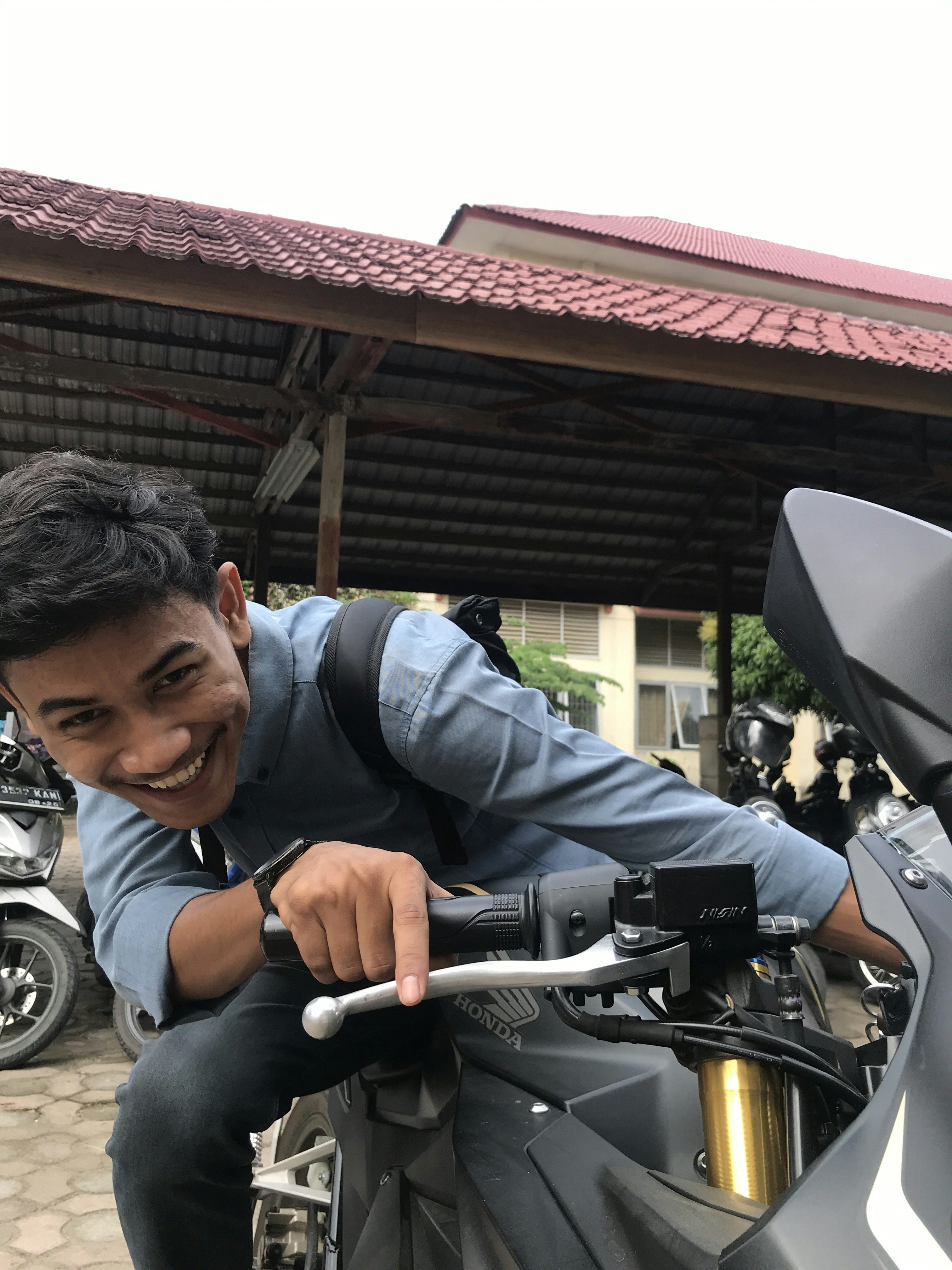 A happy customer smiling while holding motorcycle keys in front of their new bike.