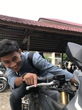 A smiling agent assisting a motorcyclist with insurance paperwork.