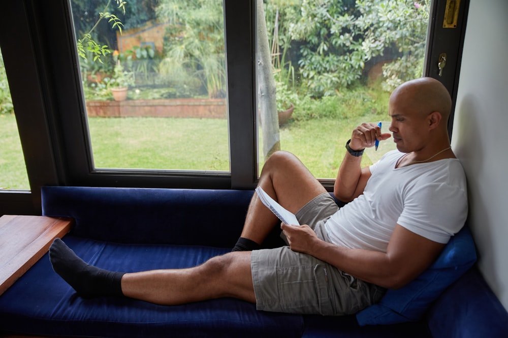 Un hombre sentado en un sofá azul mirando por una ventana