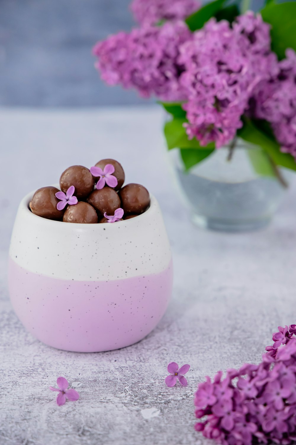 a white bowl filled with chocolates next to purple flowers