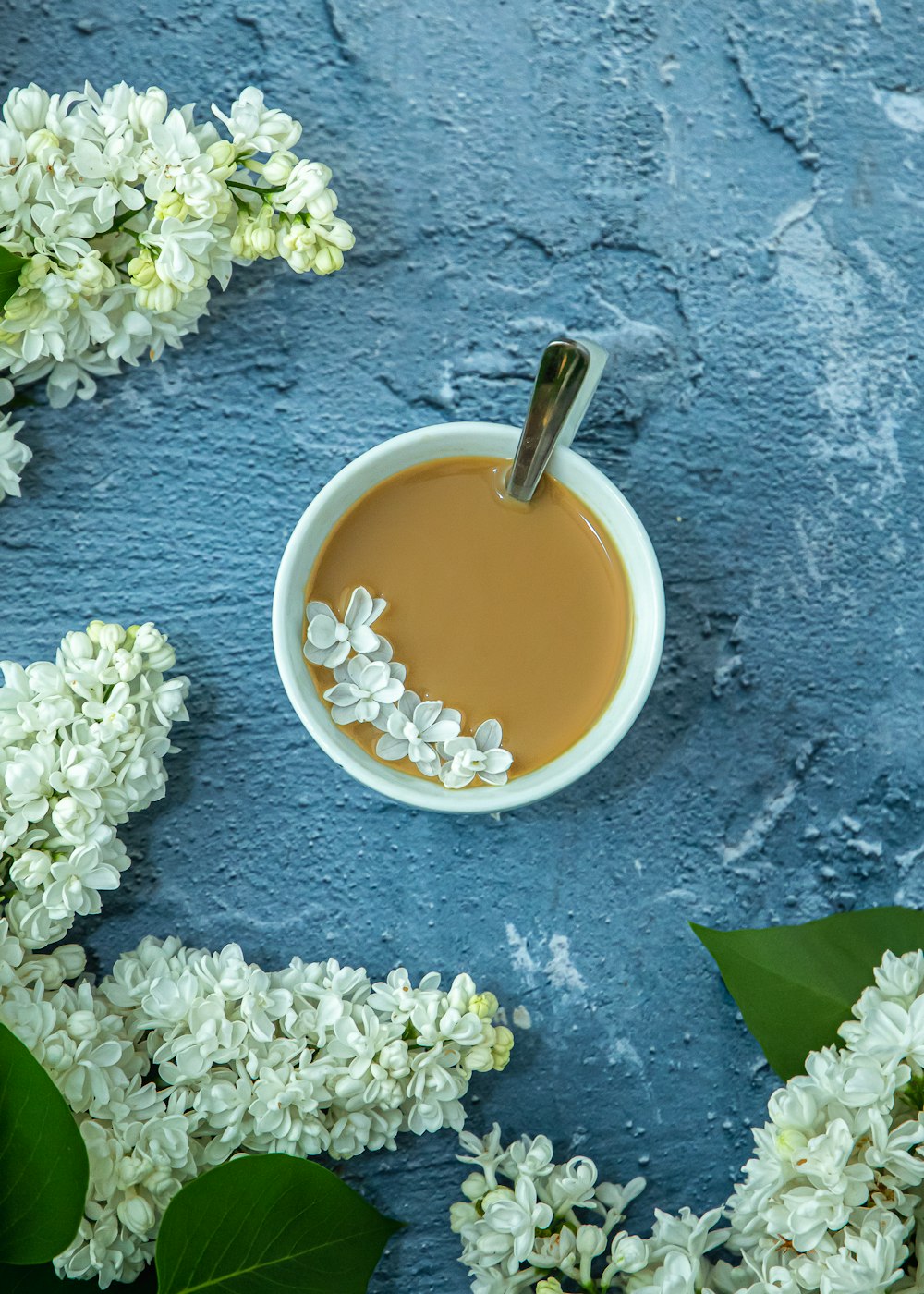 a cup of coffee surrounded by white flowers