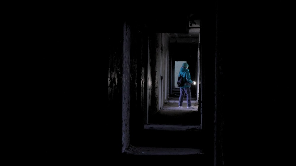 una persona in piedi in un corridoio buio con una torcia elettrica