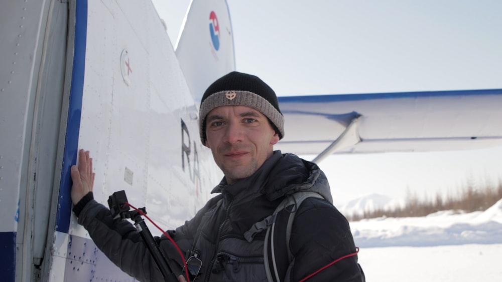 a man standing next to an airplane in the snow