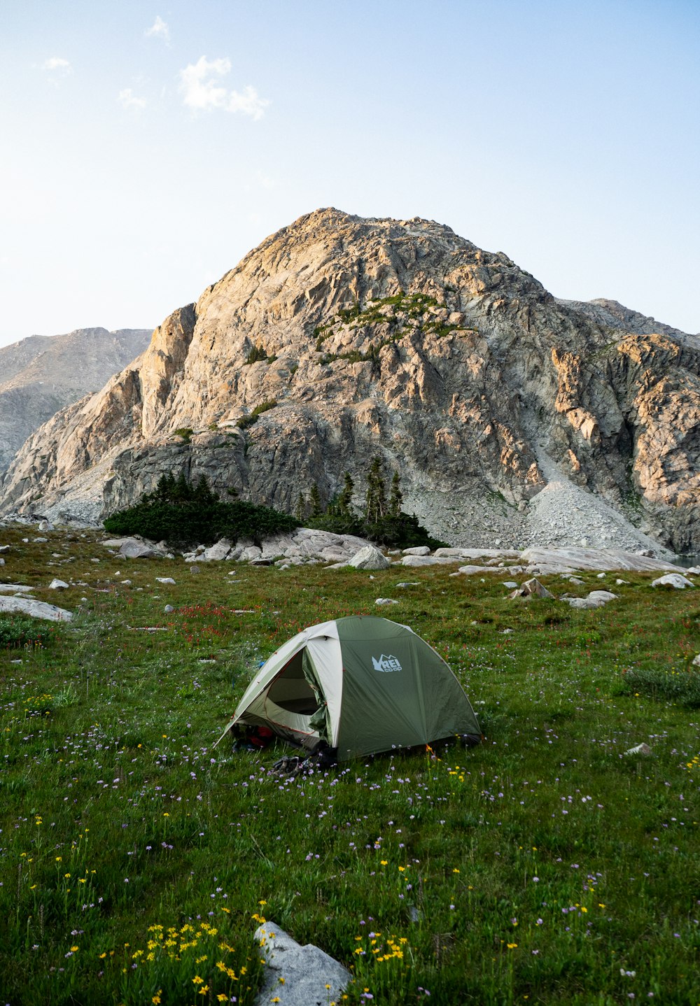 a tent pitched up in a field with a mountain in the background
