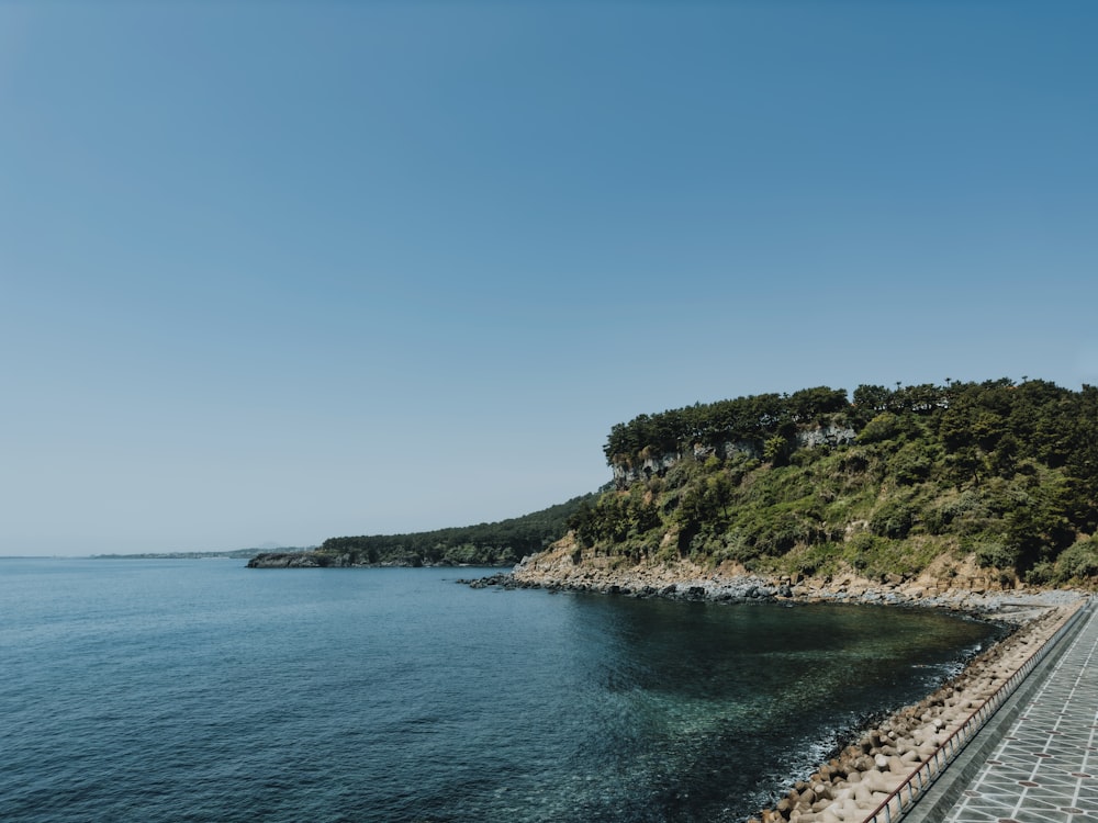 a large body of water next to a lush green hillside