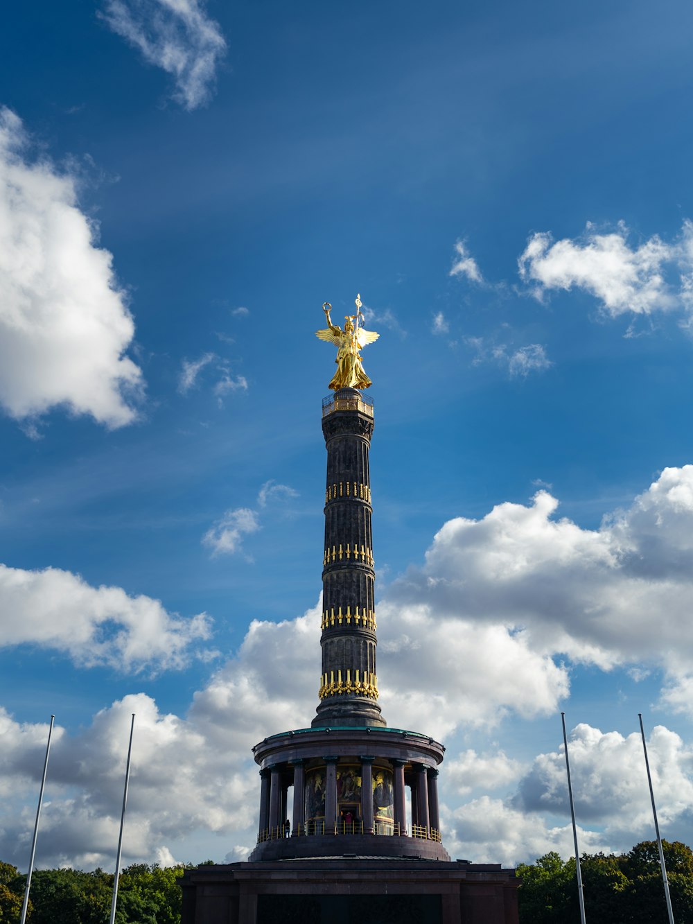 a tall tower with a golden statue on top of it