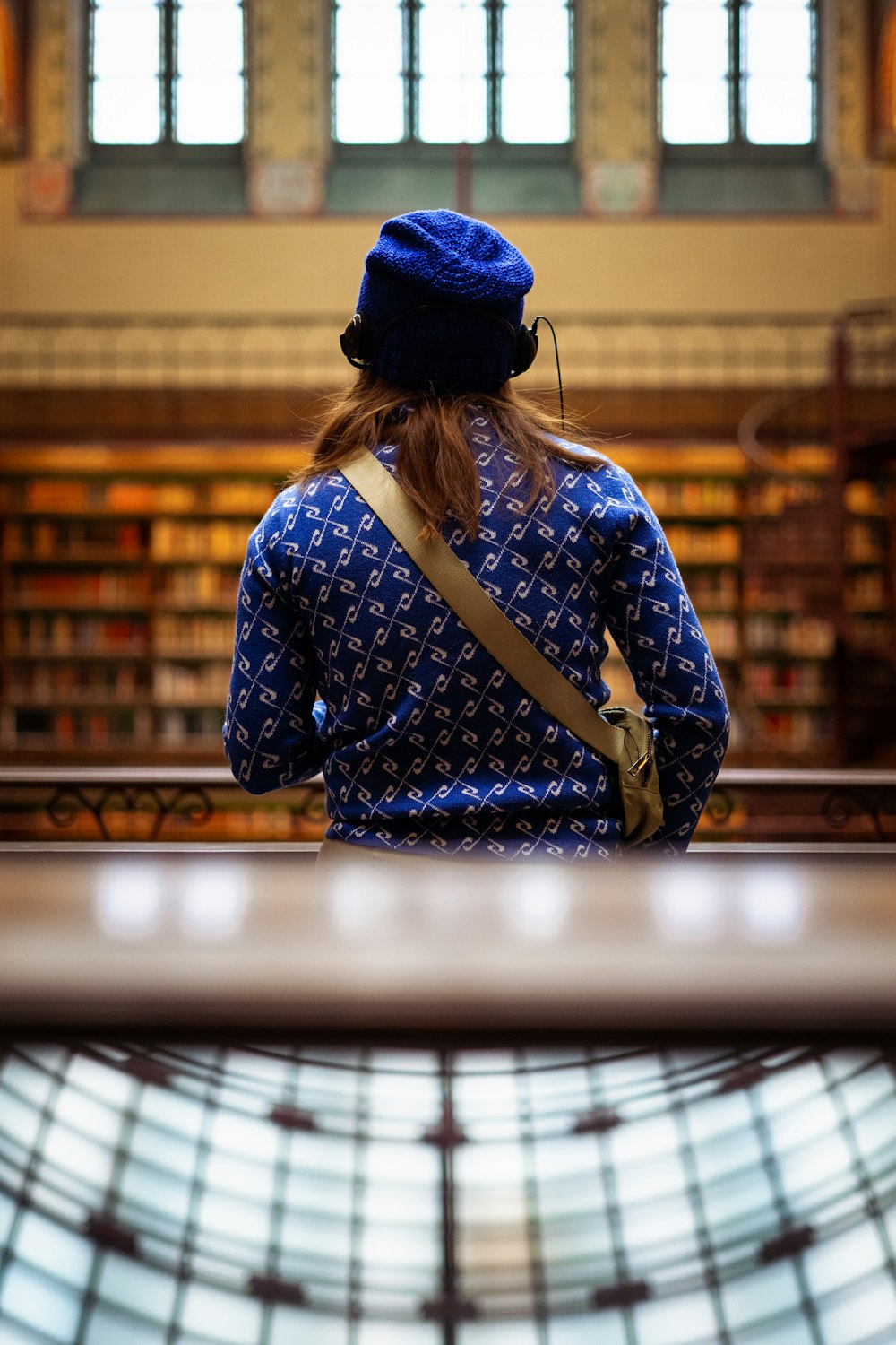 a woman with a blue hat is looking at a book shelf