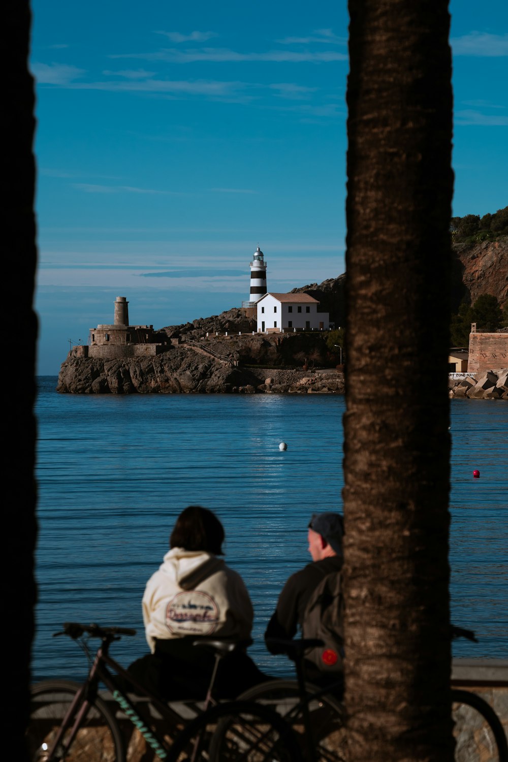 a couple of people sitting on a bench next to a body of water