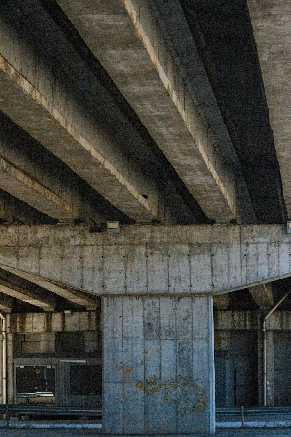 an empty parking garage under a bridge with graffiti on the walls
