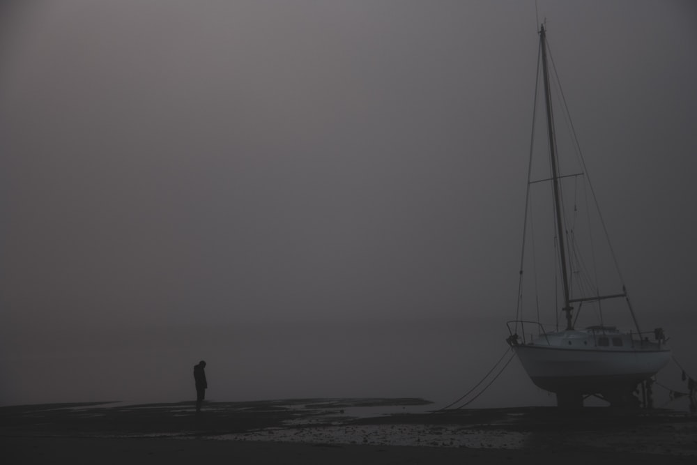 a person standing on a beach next to a boat