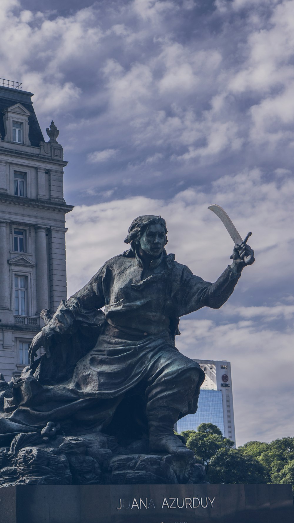 Una estatua de un hombre sosteniendo una espada frente a un edificio