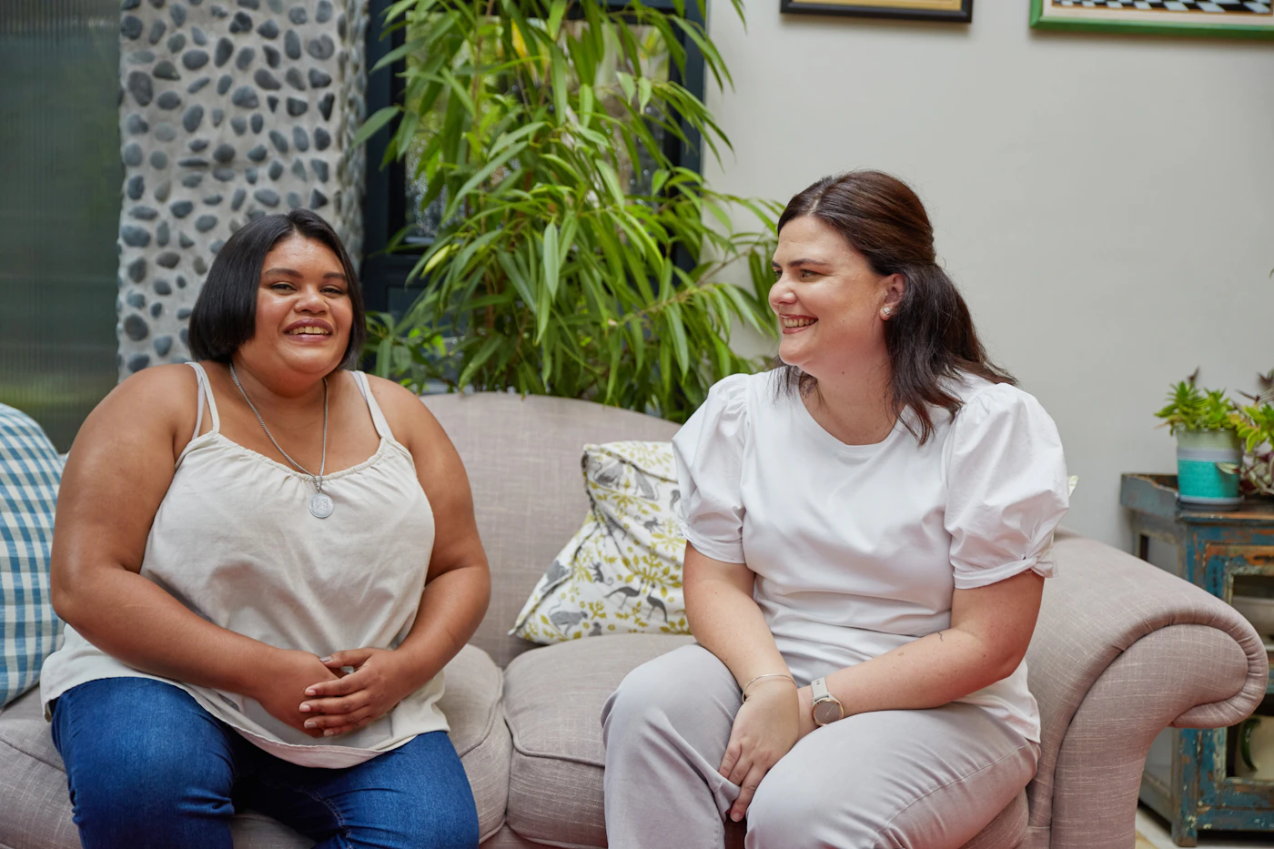 Two women talking and smiling on a sofa