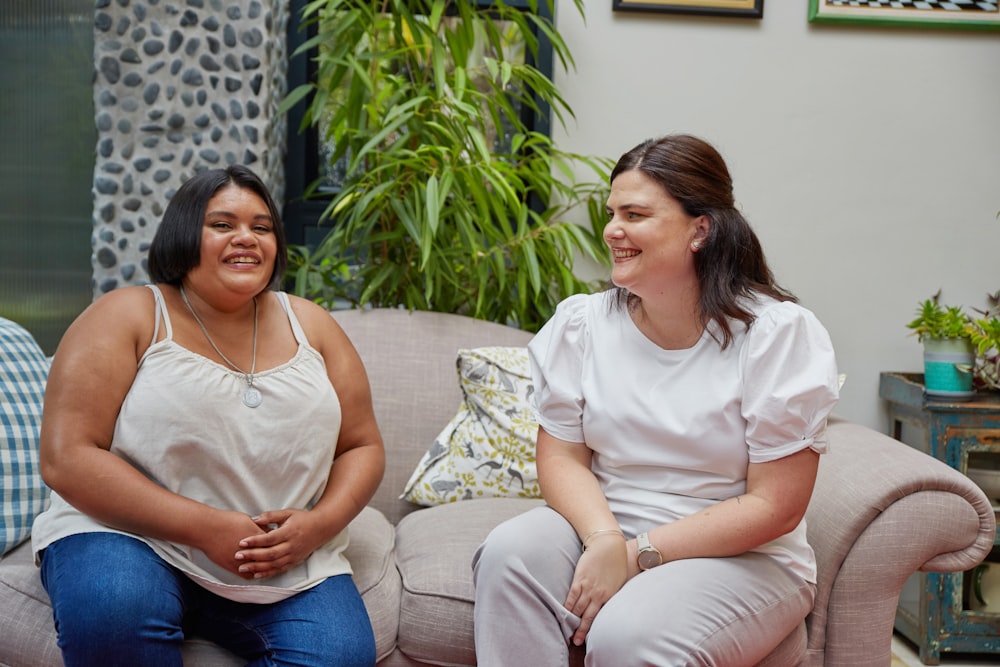 a couple of women sitting on top of a couch