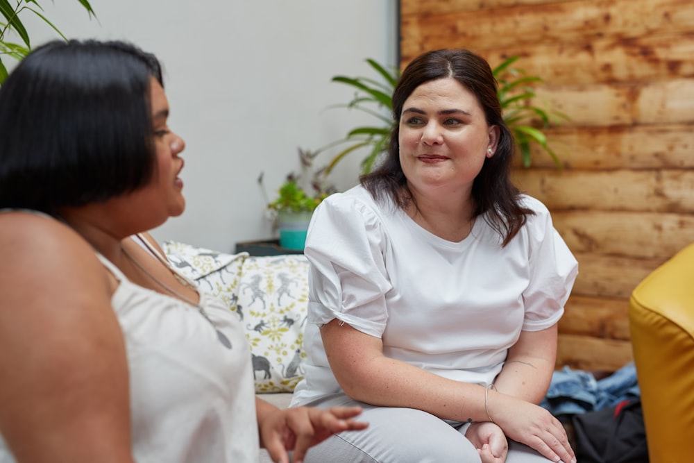 a woman sitting on a couch talking to another woman