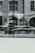 A blurred image of a car showroom, displaying a sleek sports car behind a large glass window. The reflection of a building with large windows and detailed brickwork can be seen on the glass.
