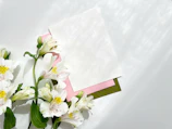 Delicate pastel flowers arranged beside a neatly stacked pile of blog drafts.