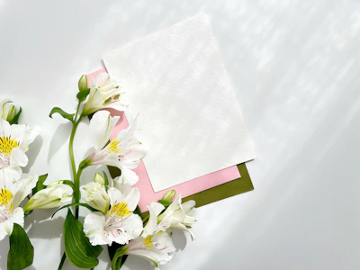 Delicate pastel flowers arranged beside a neatly stacked pile of blog drafts.