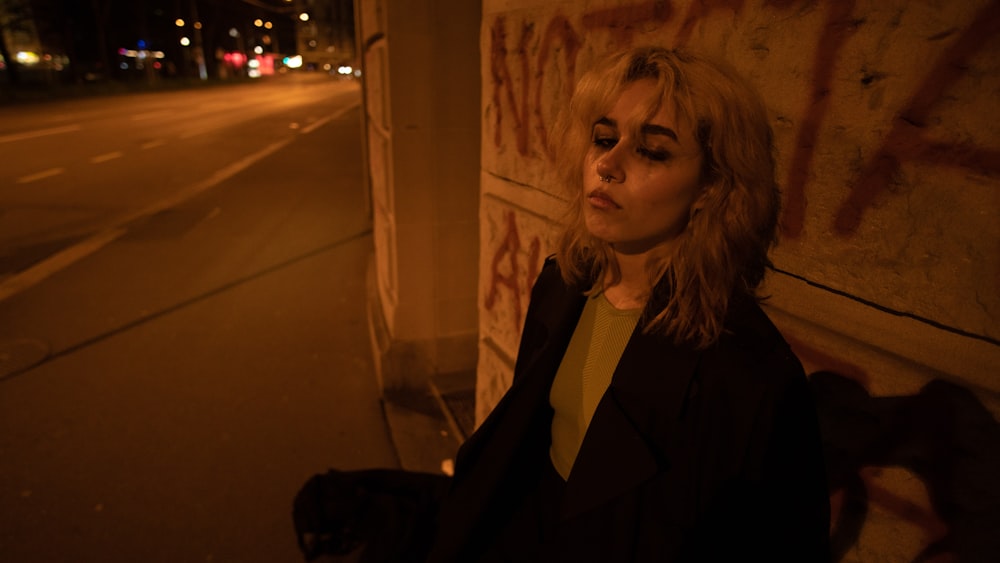 a woman standing next to a wall with graffiti on it