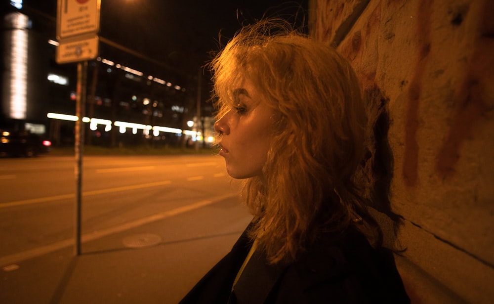 a woman leaning against a wall at night