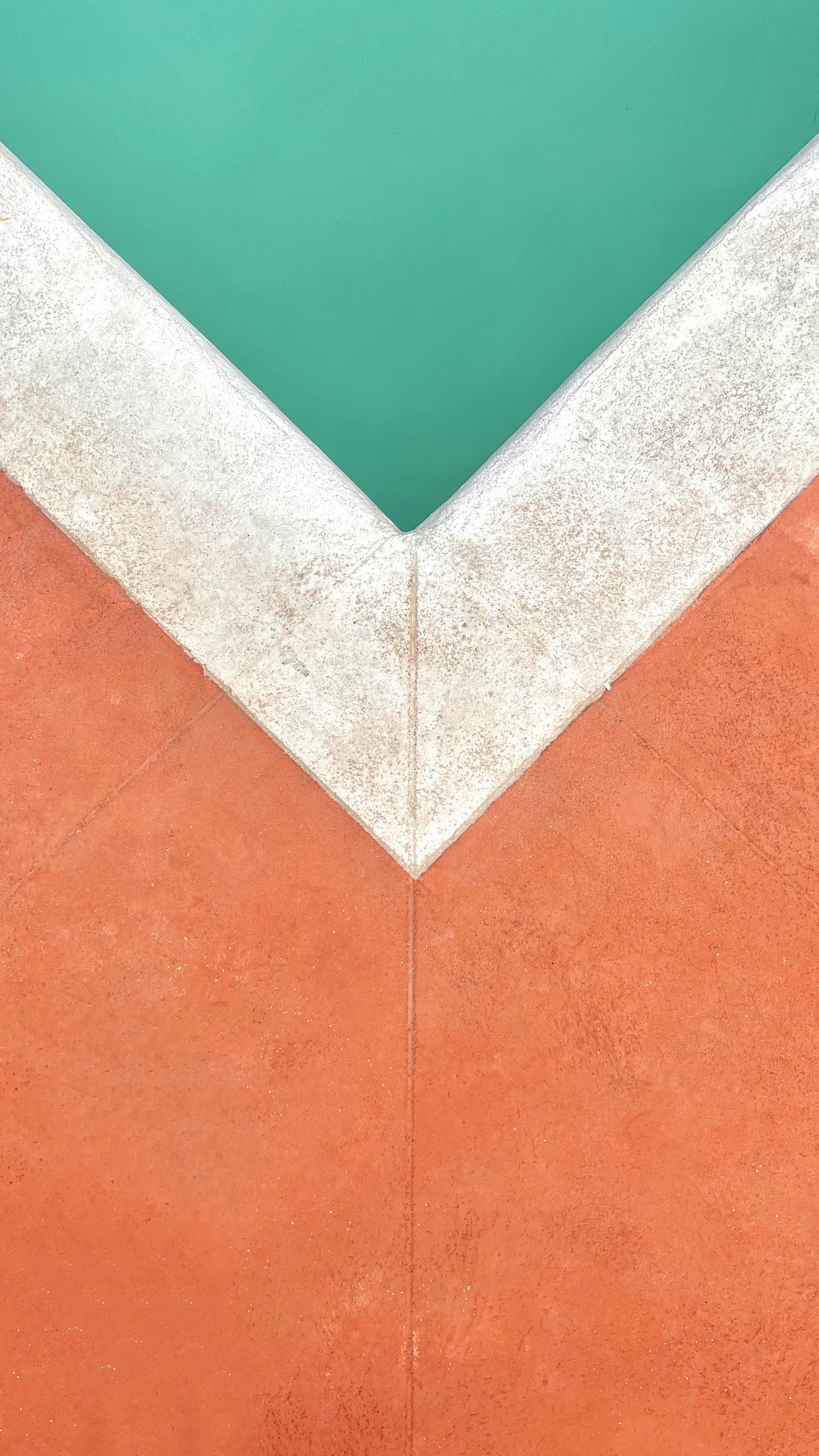 una esquina de una pared de cemento con una piscina verde en el fondo