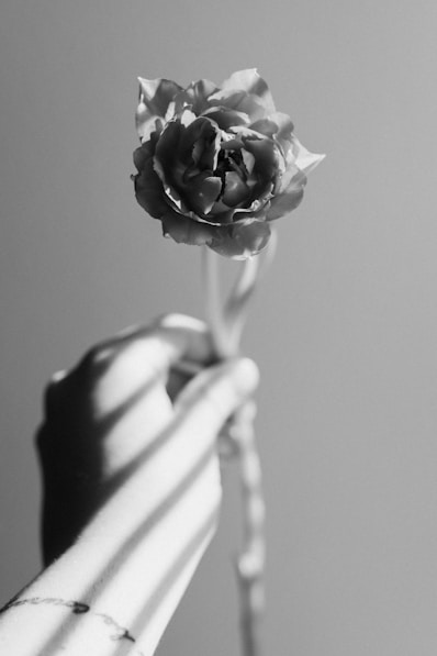 a black and white photo of a person holding a flower