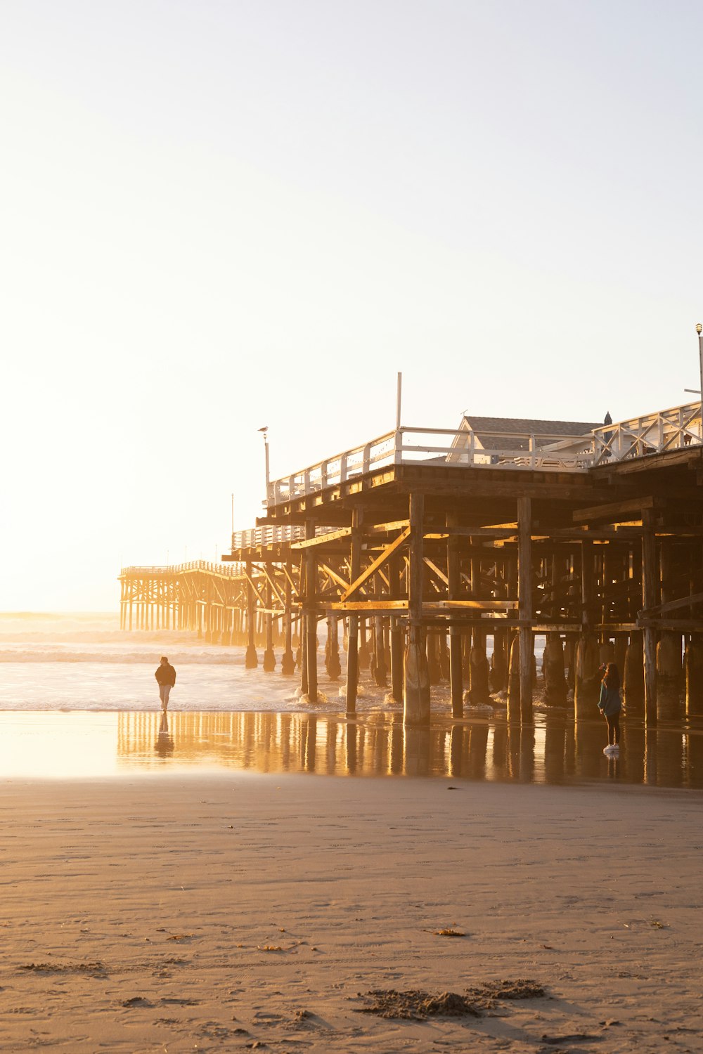 a person walking on a beach next to a pier