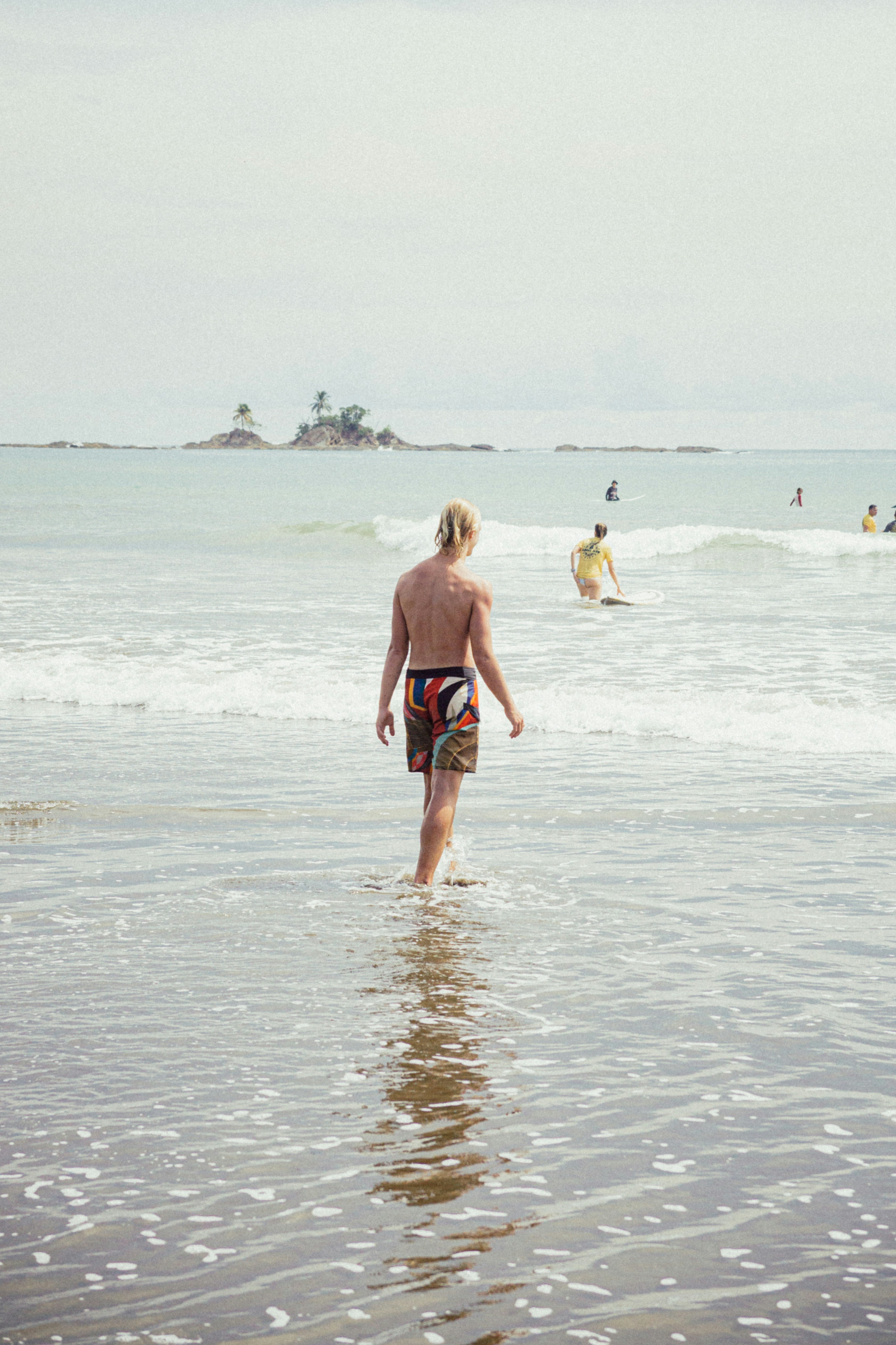 a man walking into the ocean with a surfboard