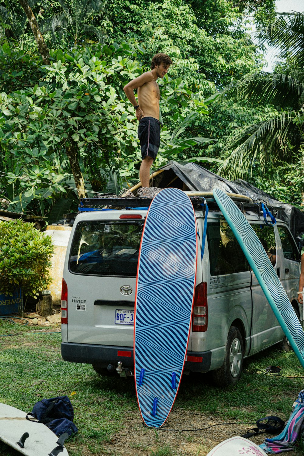 a man standing on top of a surfboard next to a van
