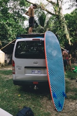A friendly driver assisting a passenger into a wheelchair-accessible van with a scenic Hawaiian backdrop.
