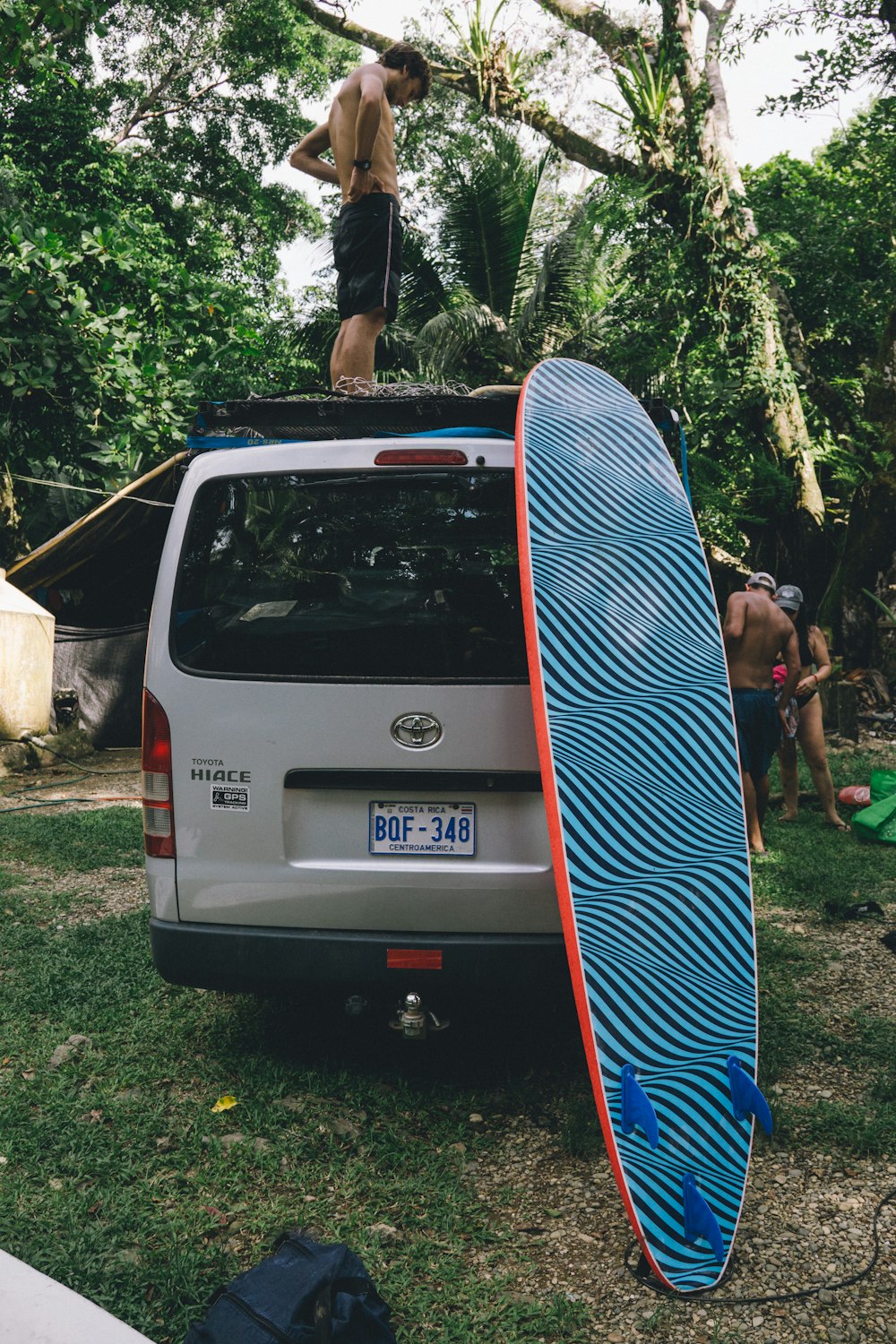 a man standing on top of a surfboard in the back of a van