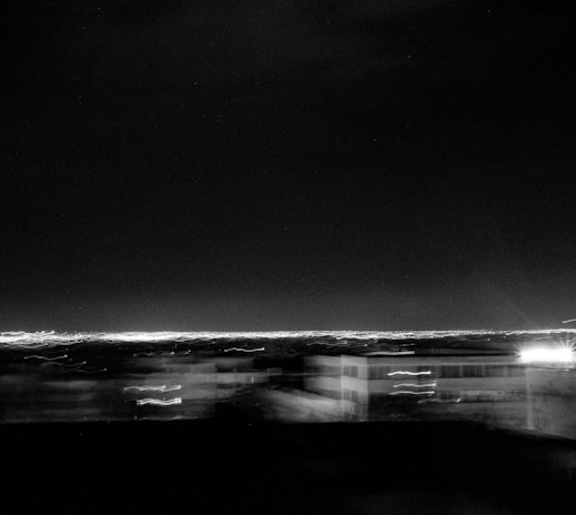 Dark, moody black and white cityscape with blurred lights and strong contrasts.