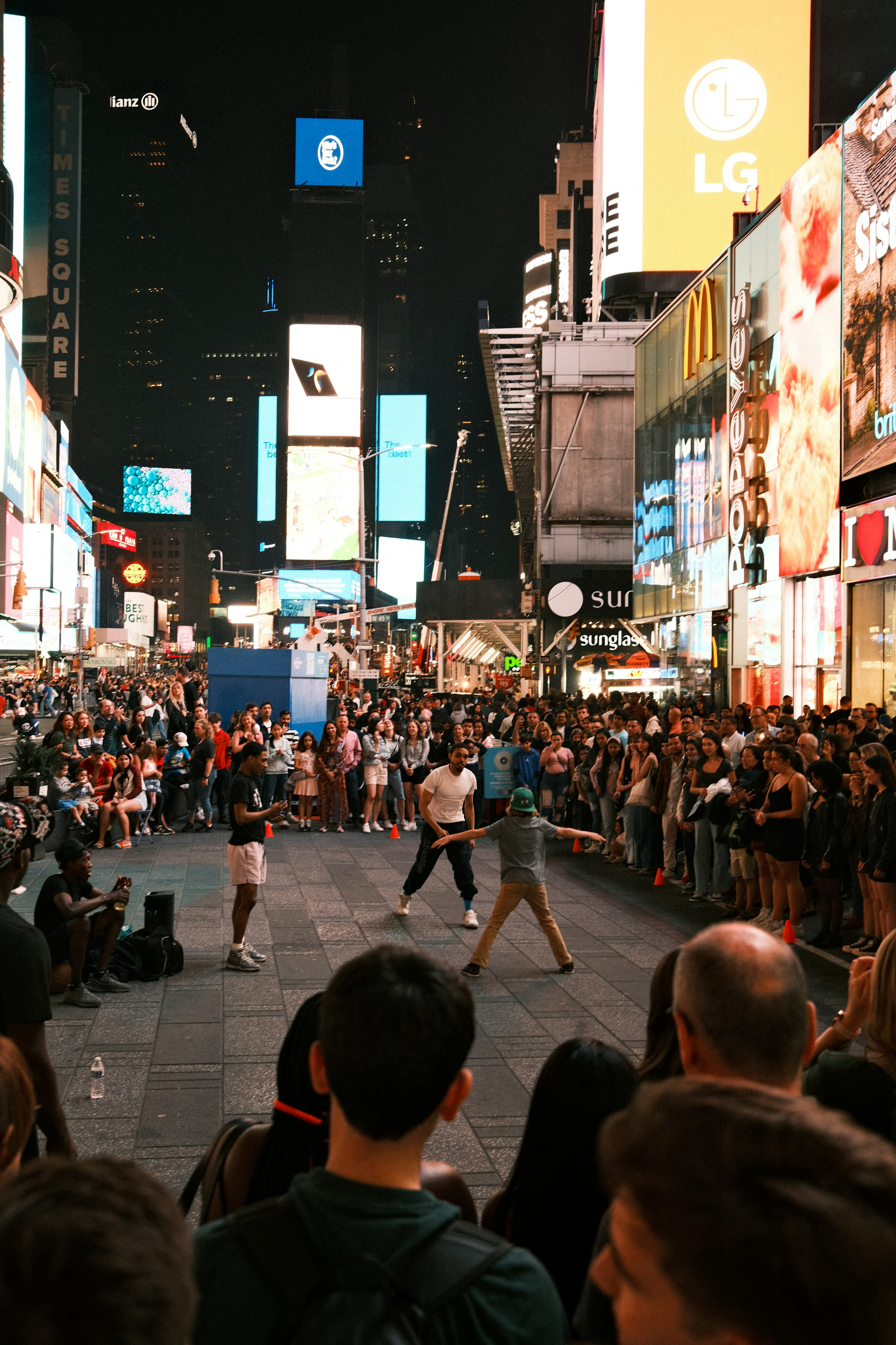 Crowded Times Square at night with a street performer surrounded by spectators