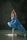 A person is gracefully balancing in a yoga pose on a rock surrounded by water. They are wearing a flowing blue garment and have their hands raised above their head in a prayer position. The background is a dark, natural setting.