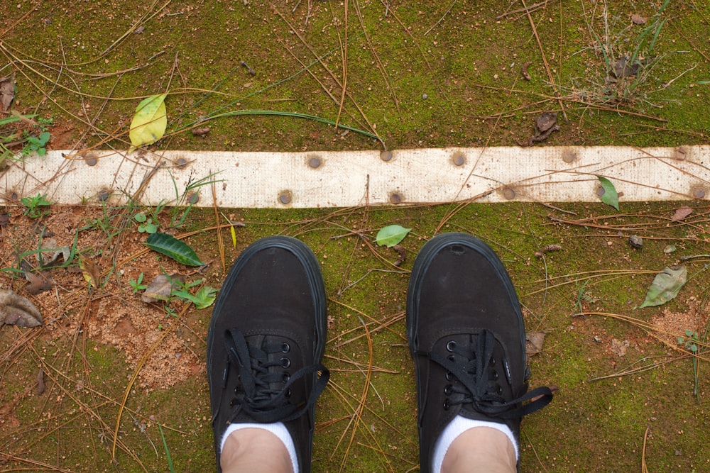 a pair of black shoes standing on top of a grass covered field