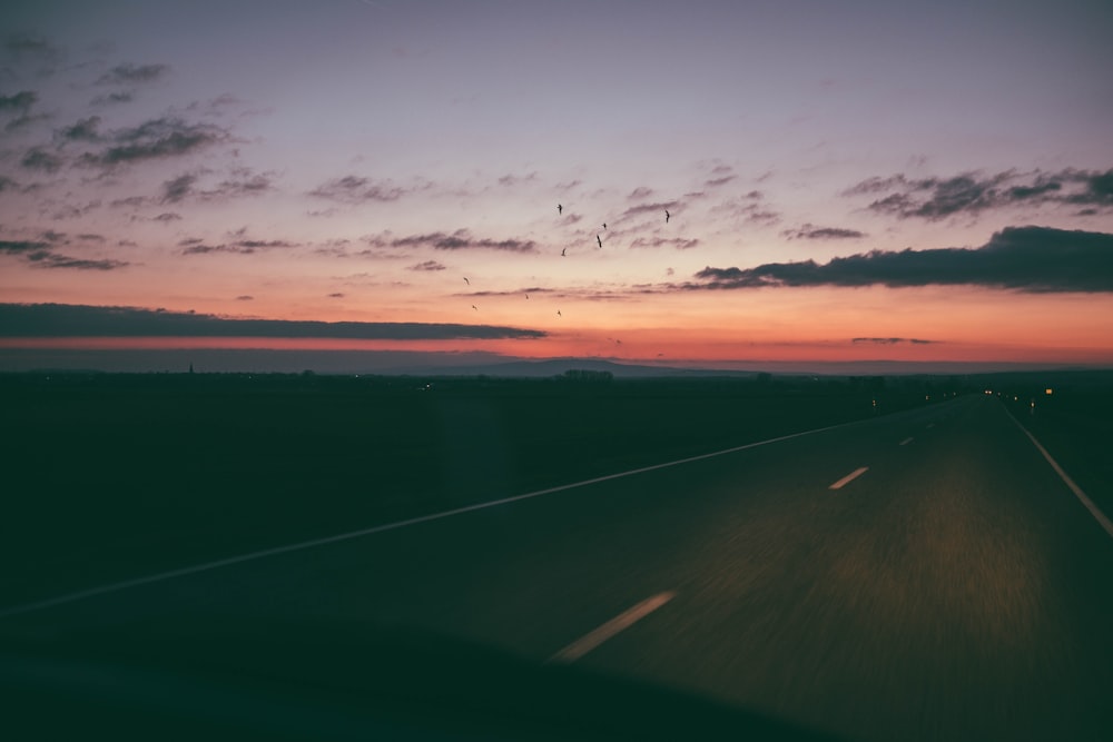 a car driving down a highway at sunset