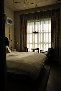 Elegant bedroom with large windows and soft linens.