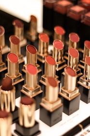 Brightly colored lipsticks arranged in a neat row on a soft pink background.