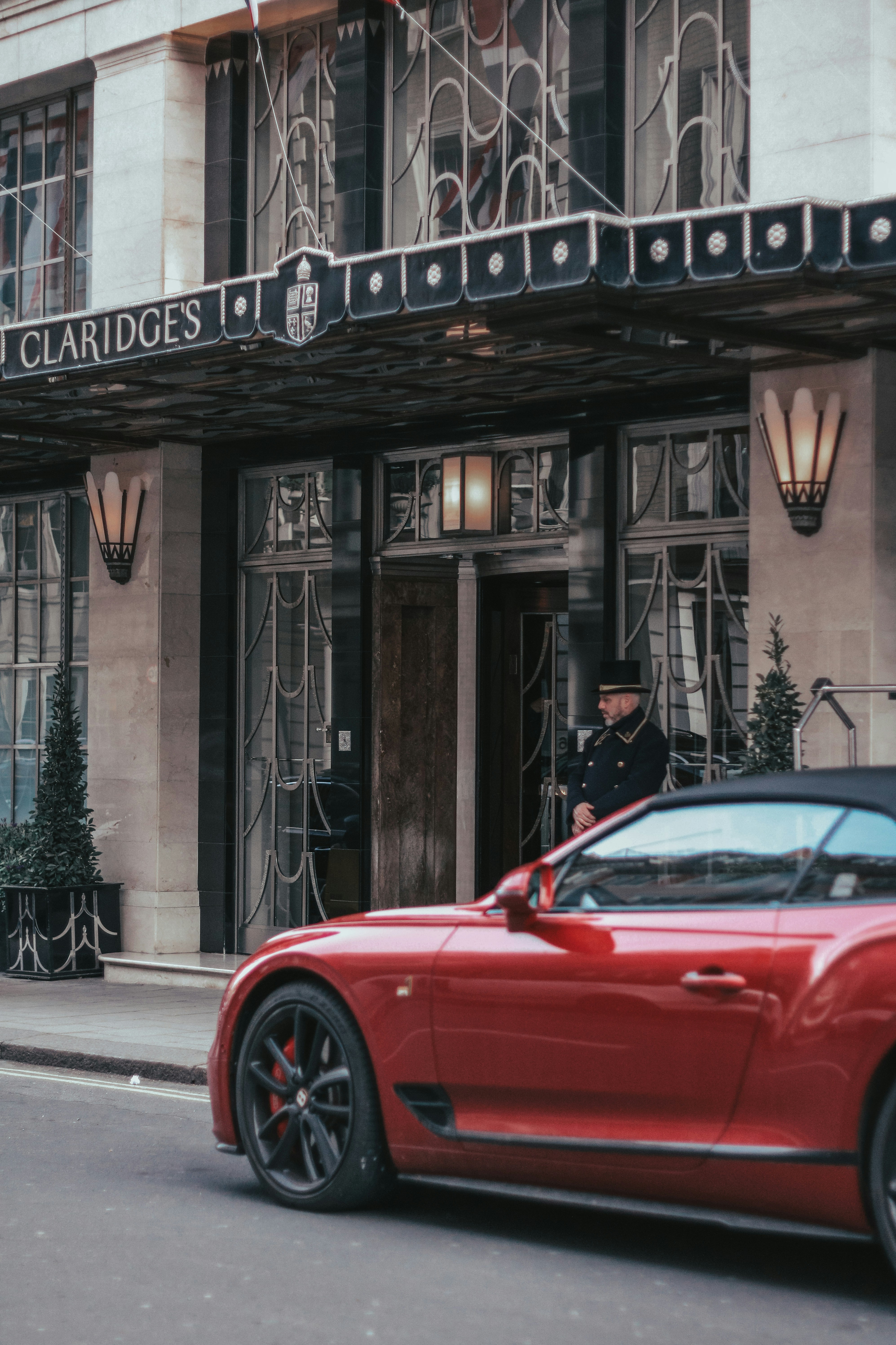 Doorman in uniform stands outside a luxury hotel entrance.