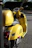 A bright yellow scooter parked by a palm tree on a sunny beach in Mauritius.