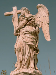 Hands holding a small statue of the Virgin Mary against a backdrop of a clear blue sky.