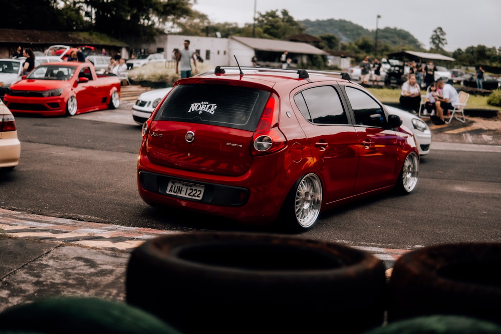 a red car driving down a street next to other cars