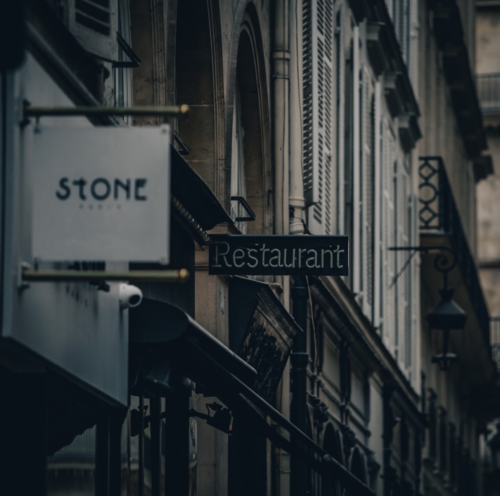 a restaurant sign hanging from the side of a building