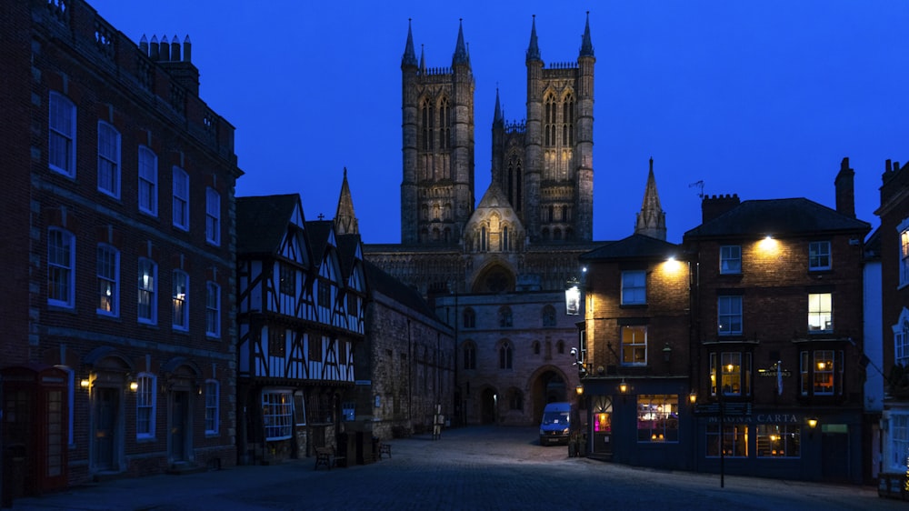 a city street at night with a cathedral in the background