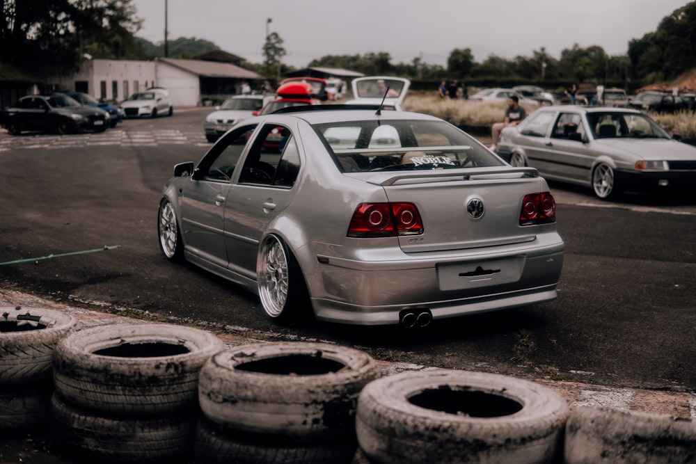 a silver car parked in a parking lot next to some tires