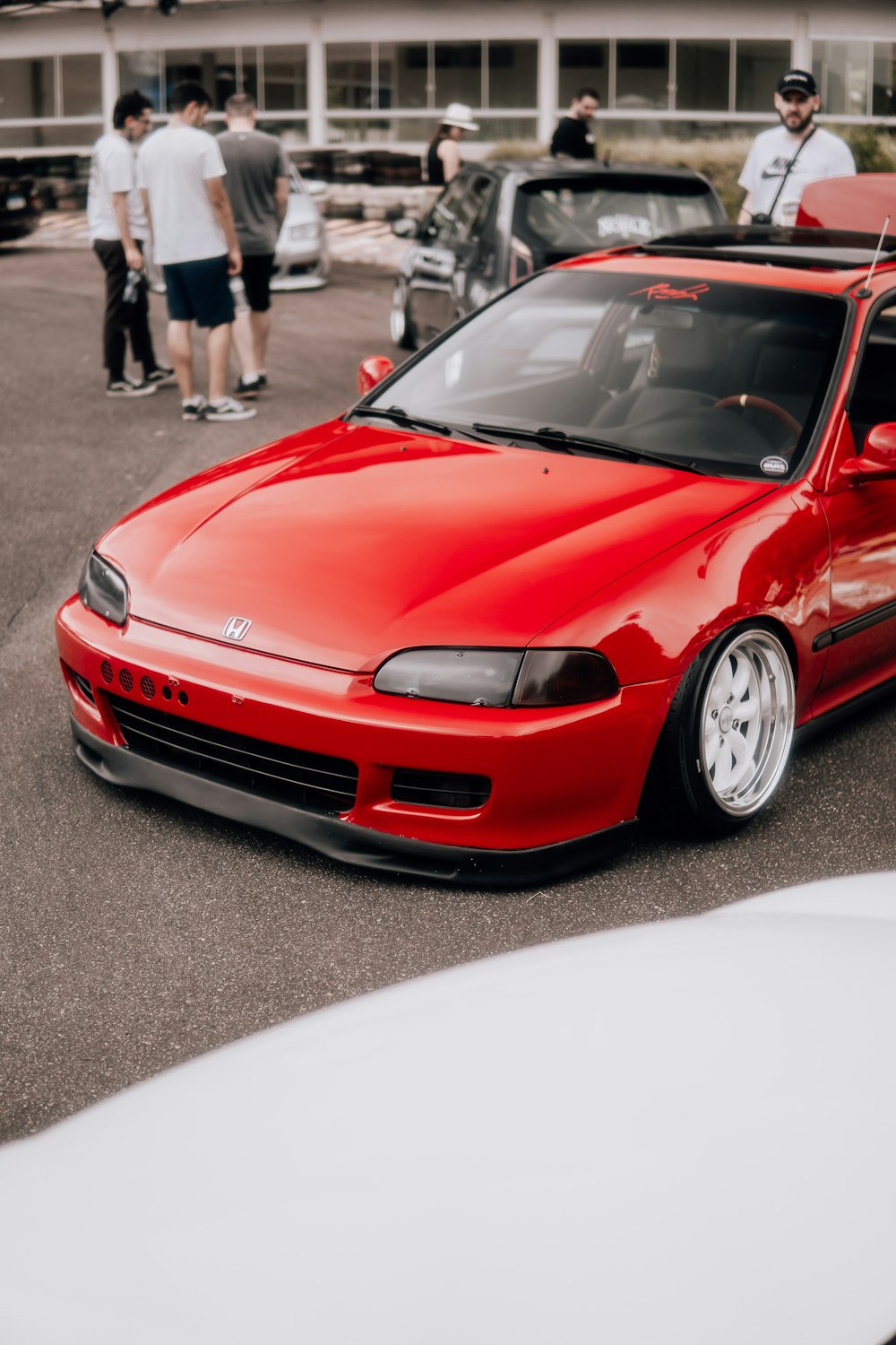 a red car parked in a parking lot next to other cars