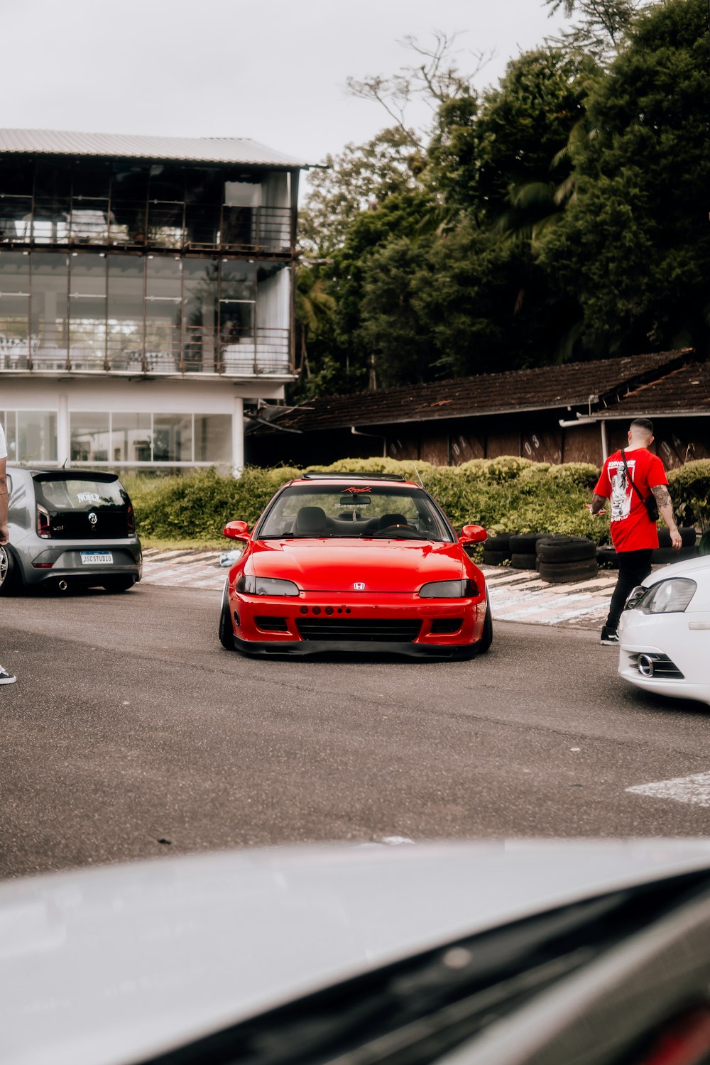 a red sports car driving down a street next to a tall building