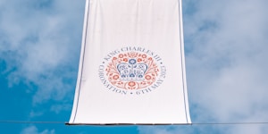 a white banner hanging from a wire with a blue sky in the background