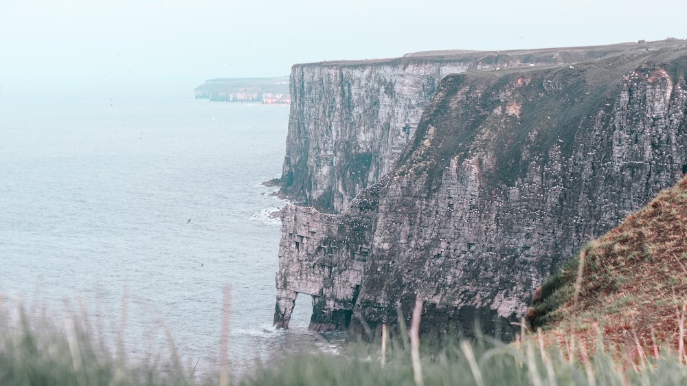 a view of a cliff with a body of water in the background