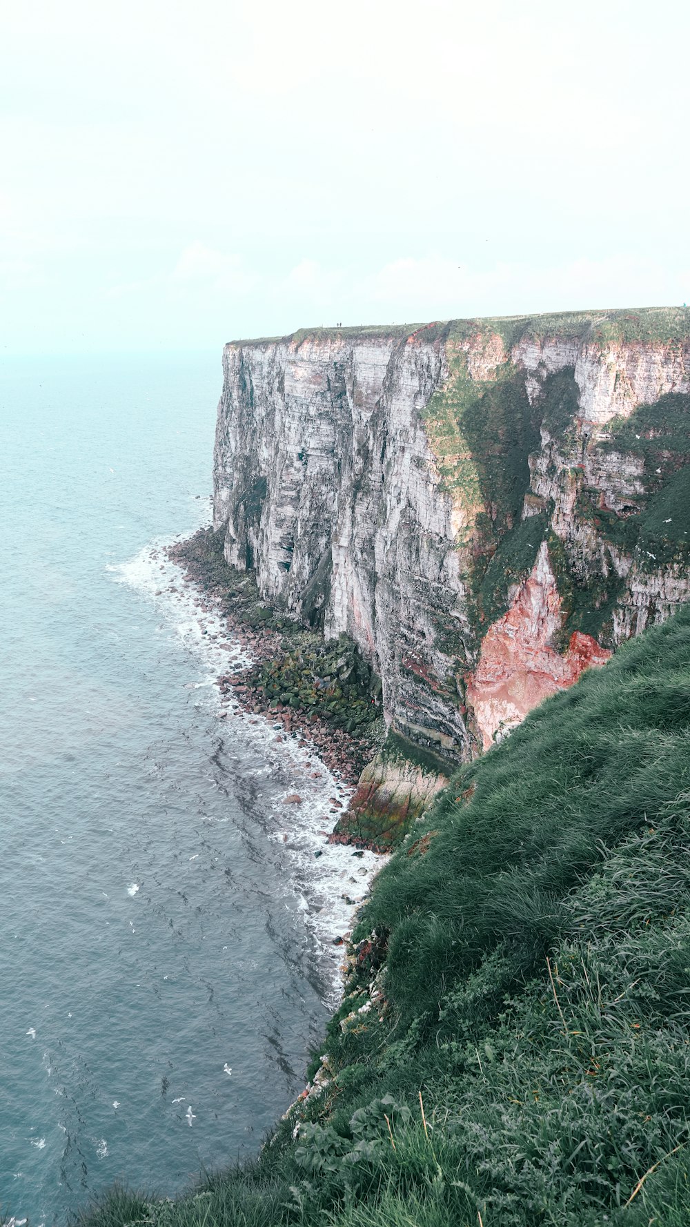 a cliff overlooking the ocean on a cloudy day